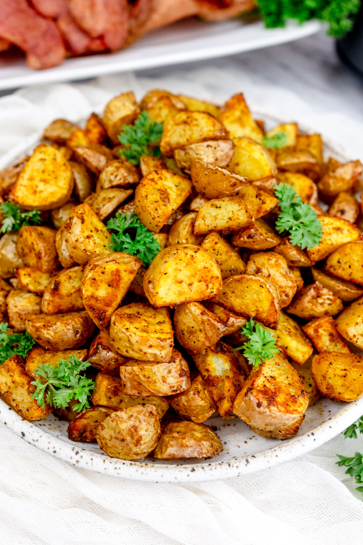 Air Fryer Breakfast Potatoes on a white plate with a leafy green garnish.