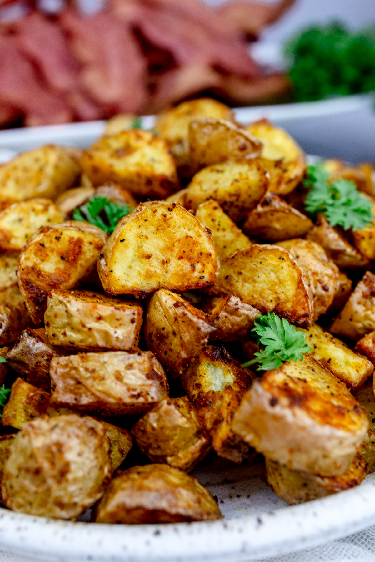 Air Fryer Breakfast Potatoes on a white plate with a leafy green garnish.