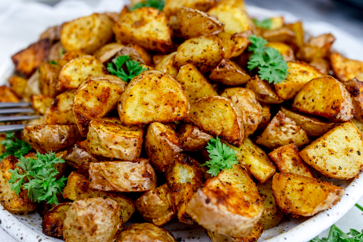 Air Fryer Breakfast Potatoes on a white plate with a leafy green garnish.