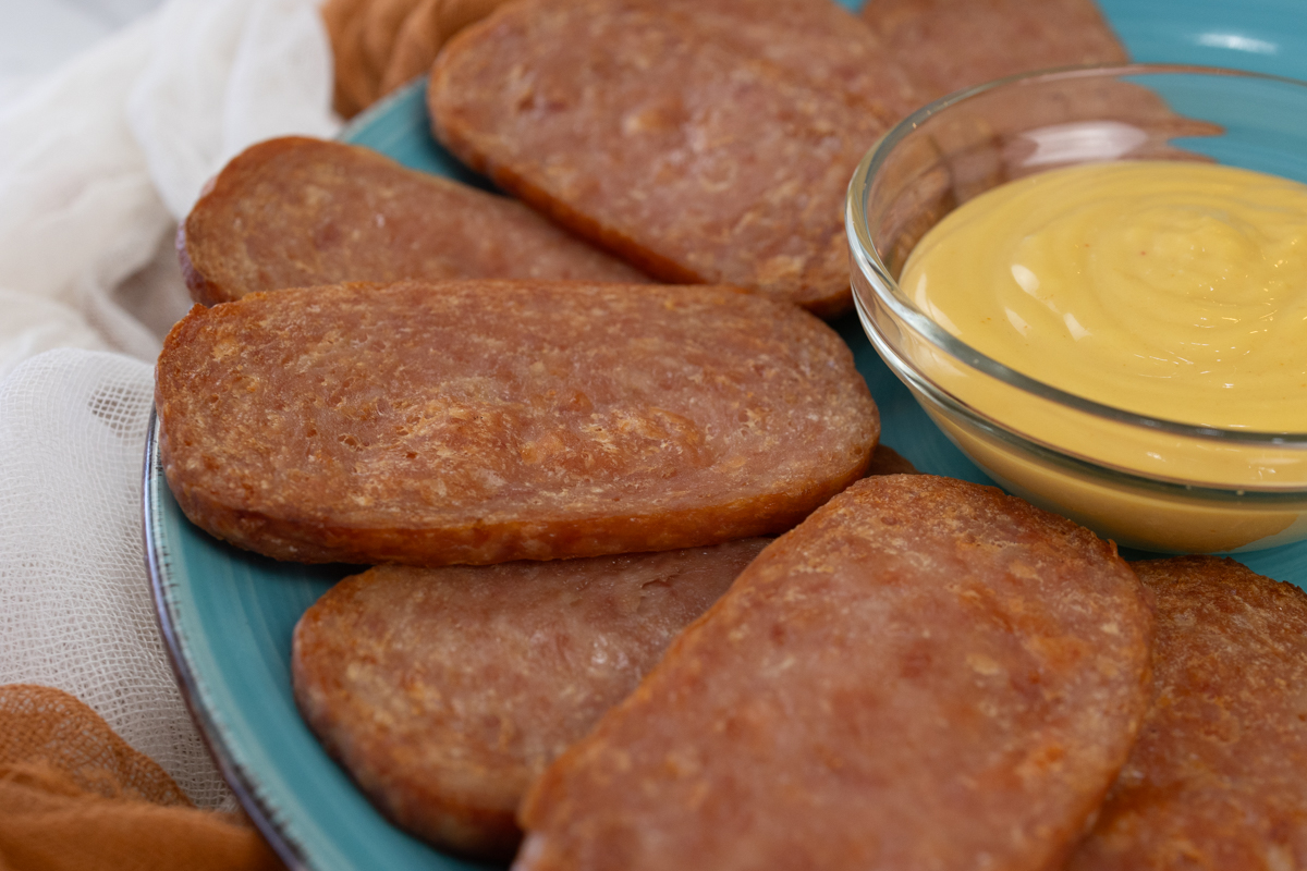 Air Fried Spam slices arranged on a blue plate around a small bowl of dipping sauce.