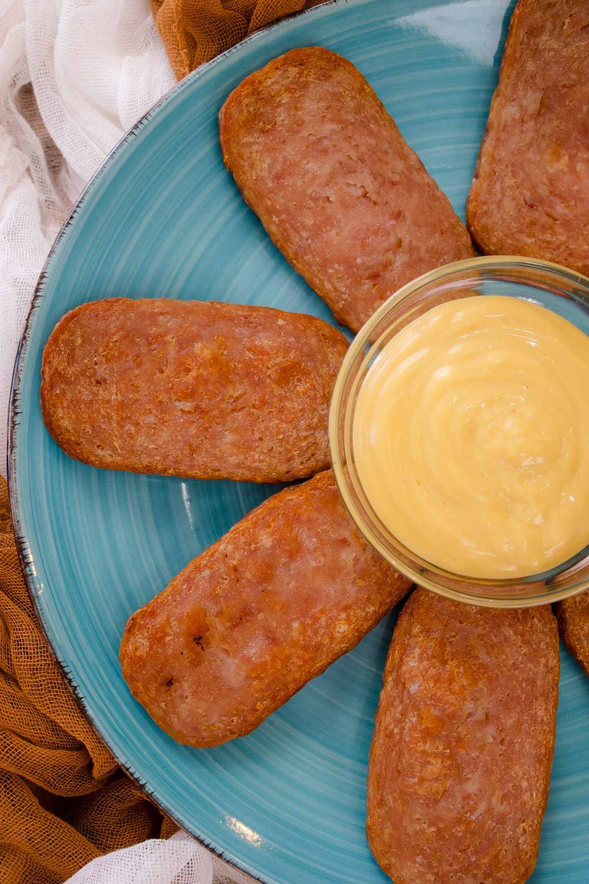Air Fried Spam slices arranged on a blue plate in a starburst formation with a small bowl of dipping sauce in the center.