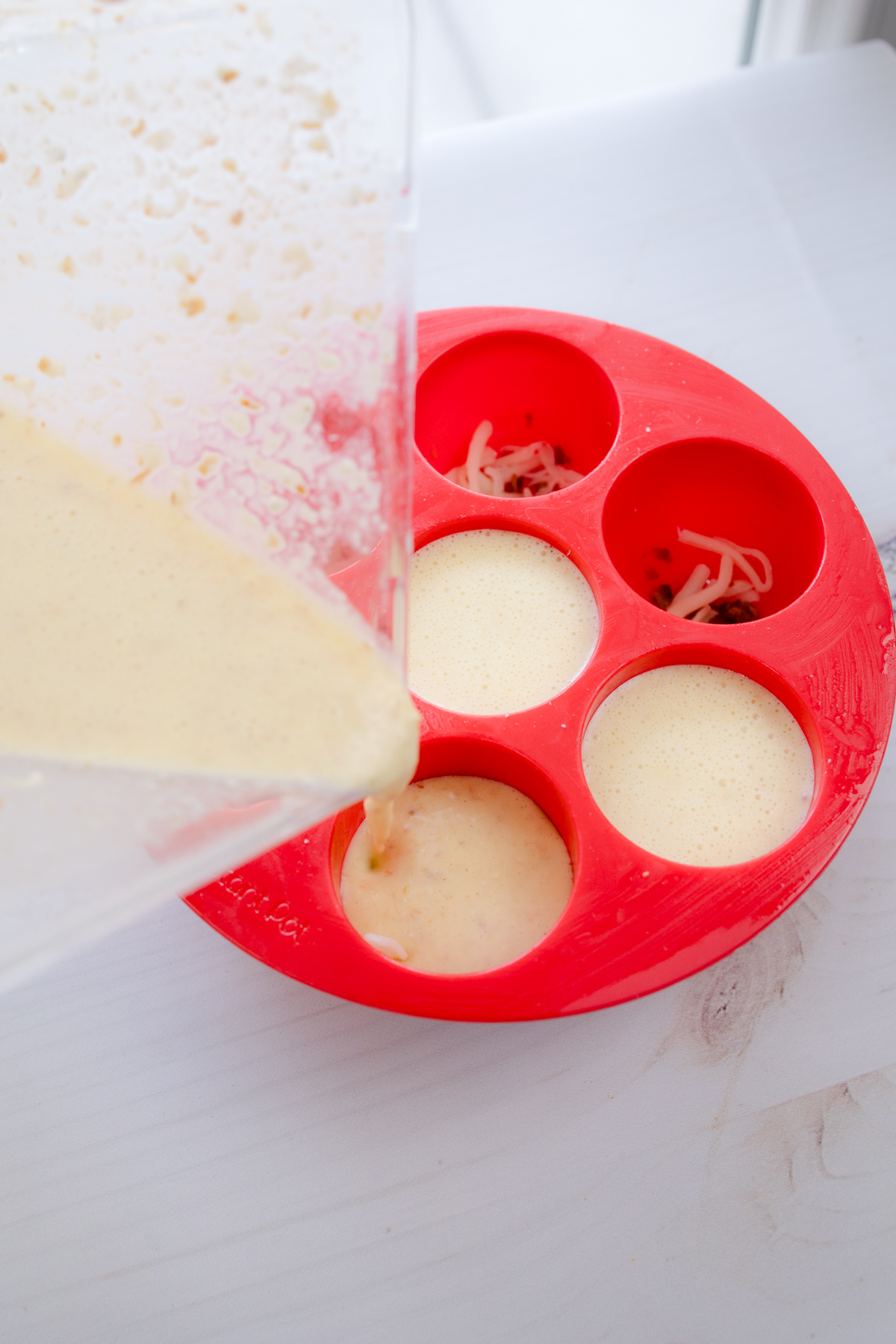 Close up shot of Air Fryer Egg Bites mixture being poured into red silicone dish.