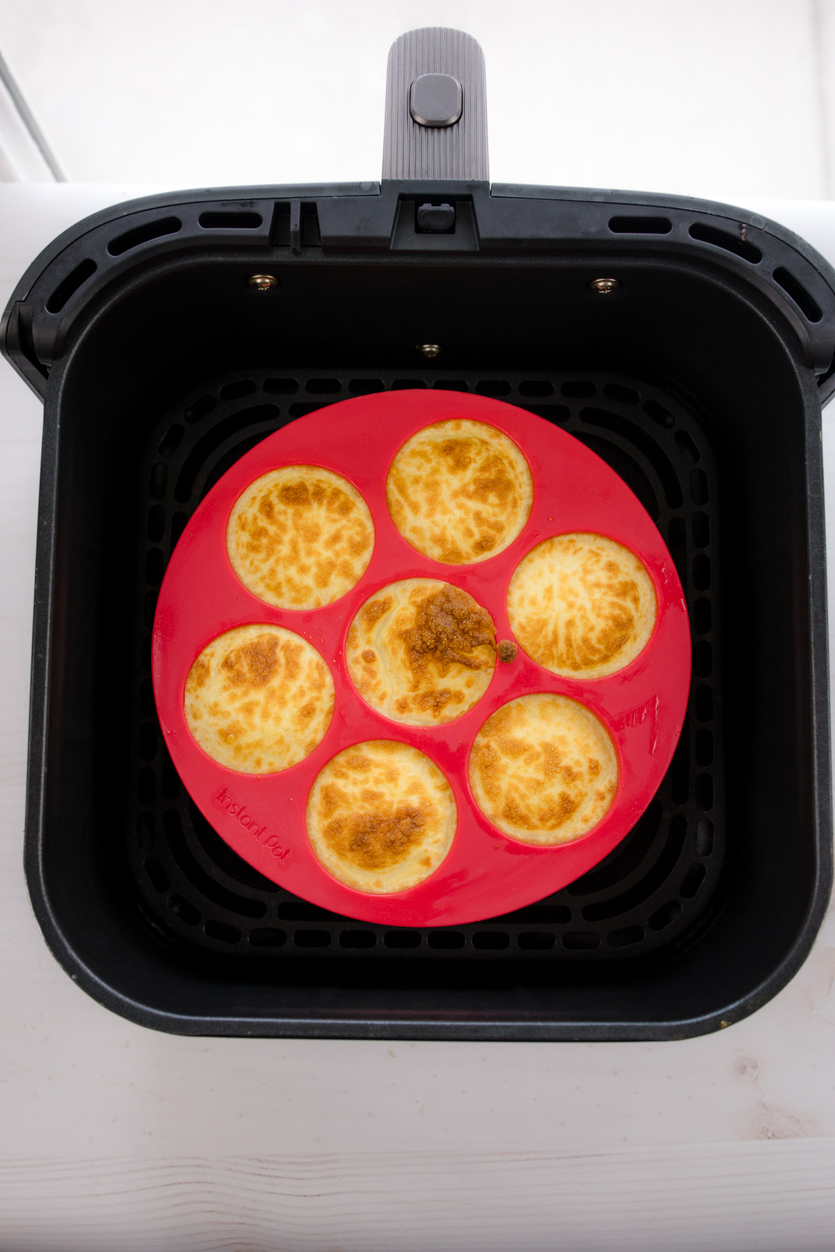 Overhead shot of red silicone dish containing egg bites in air fryer basket.