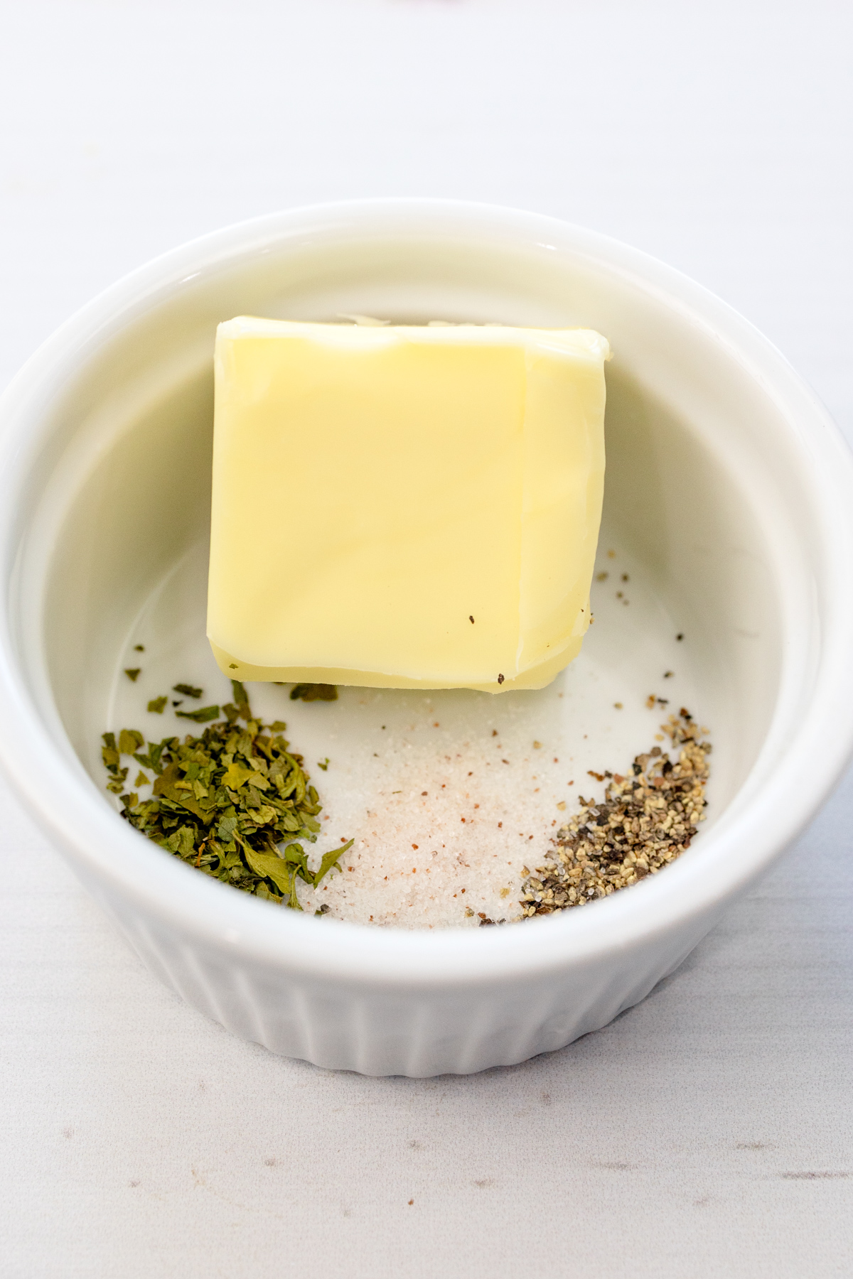 Close up image of butter and seasonings in a small bowl.