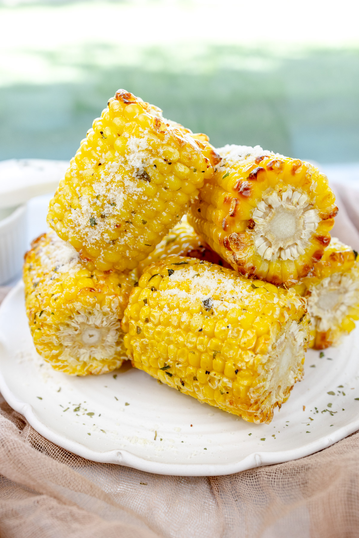 Close up image of air fried corn on the cob on a white plate.