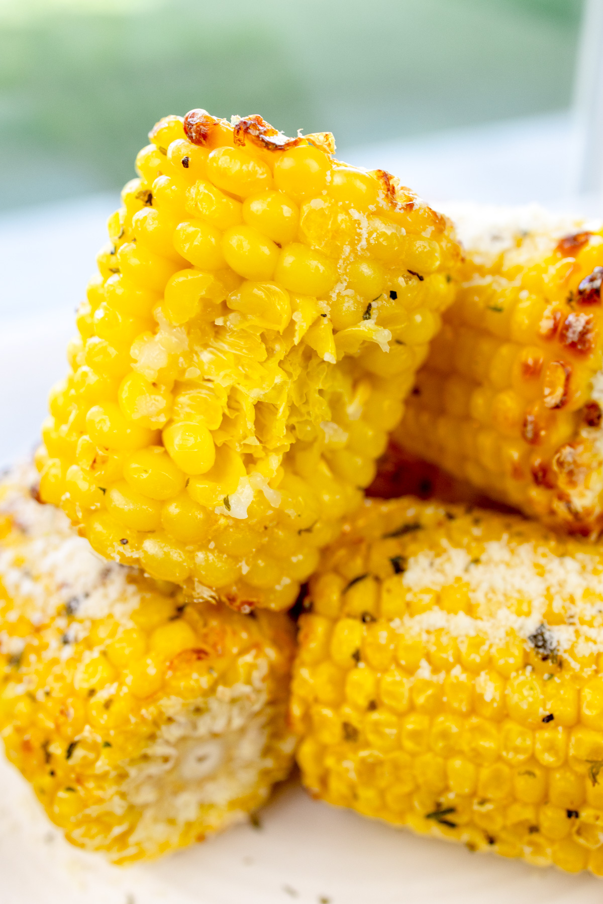 Close up image of air fried corn on the cob on a white plate.