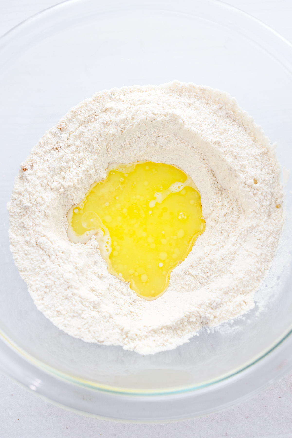Overhead image of dry ingredients needed to make Air Fryer Peach Cobbler, with a well in the middle and wet ingredients in it.