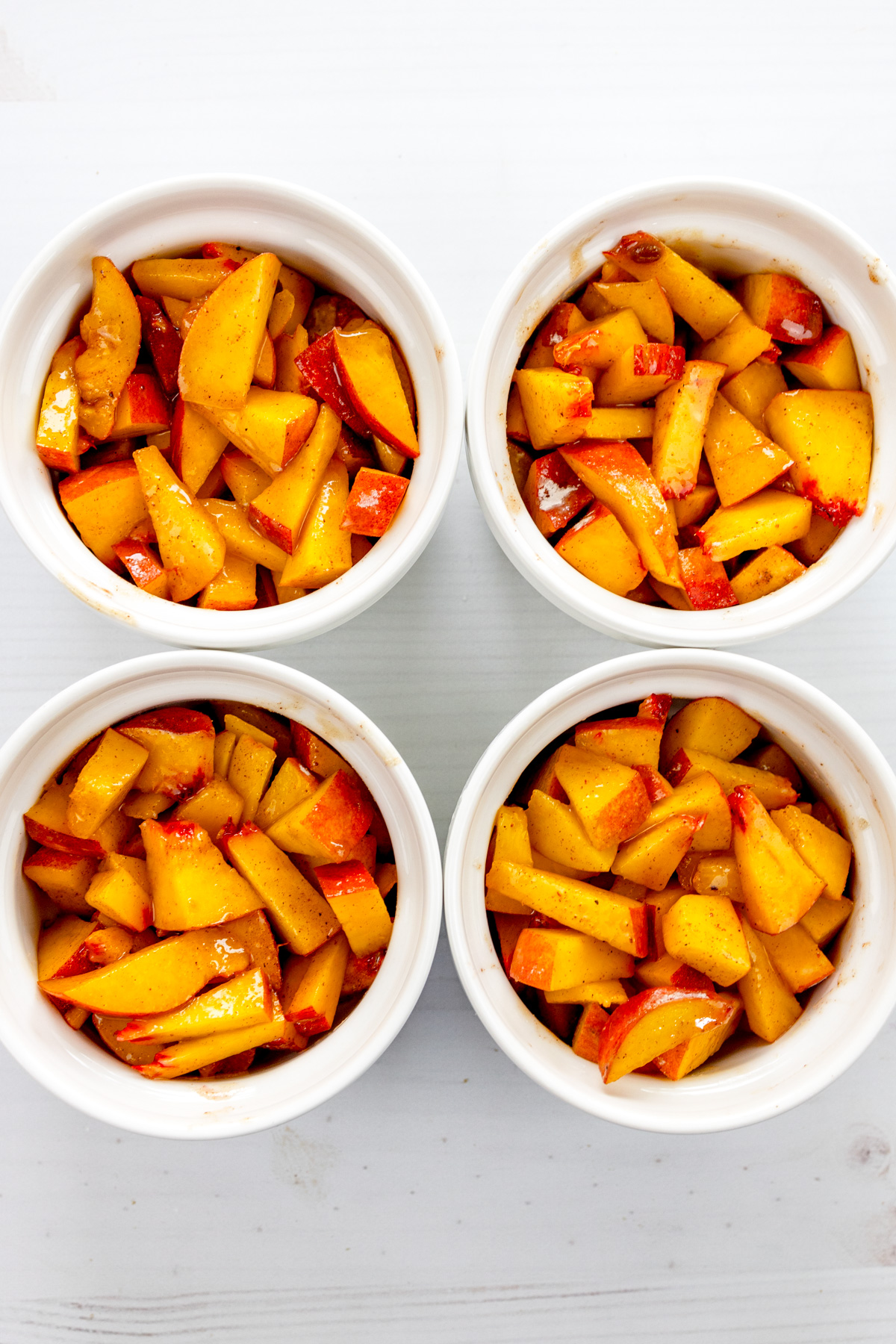 Overhead image of four ramekins filled with peach slices mixture.