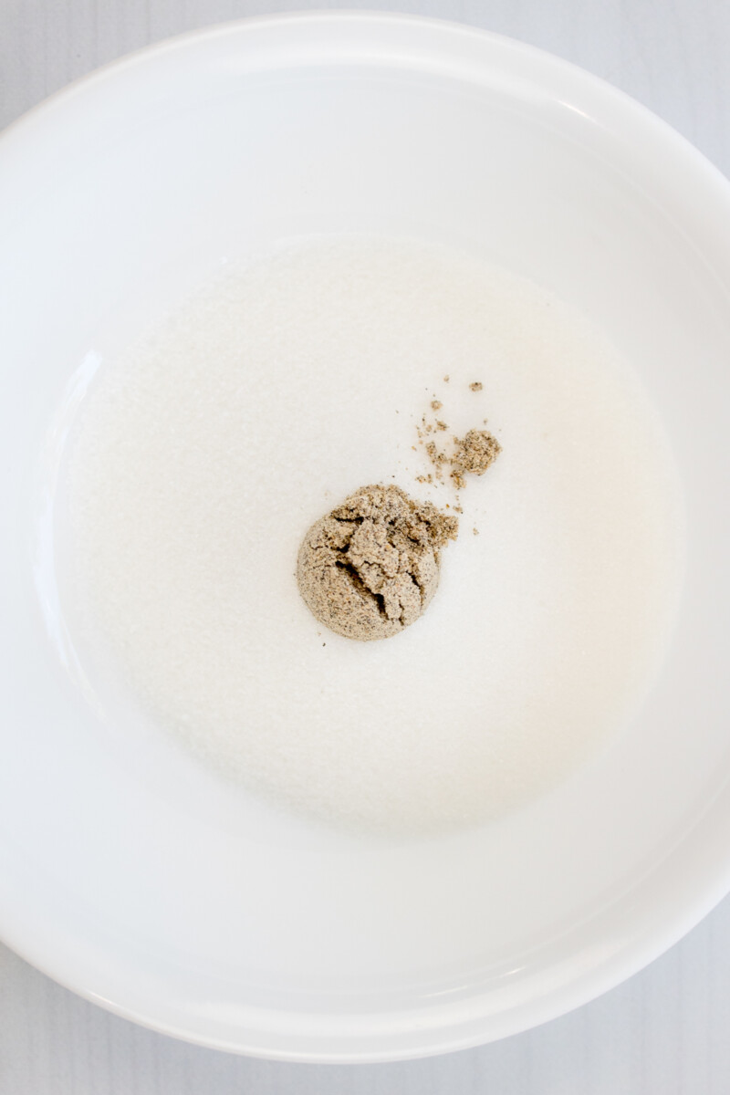 An overhead image of ground cardamom in a white bowl.
