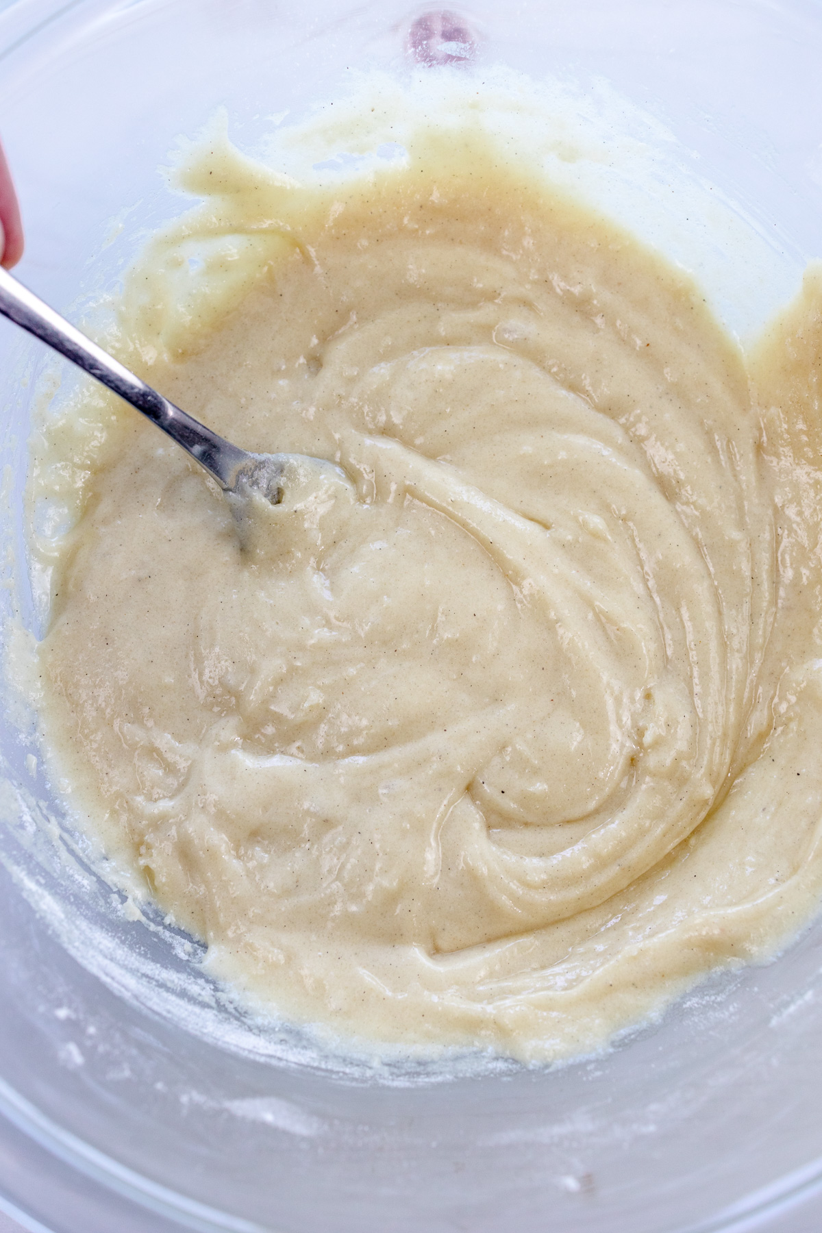 Close up image of a mixing bowl with cardamom muffin batter in it.