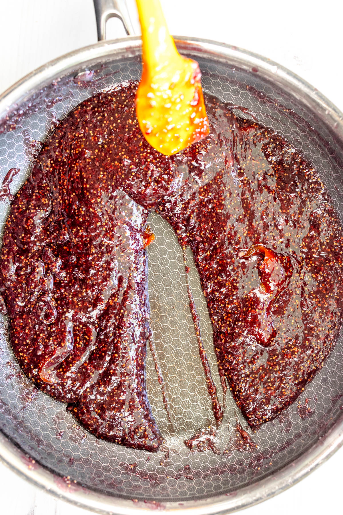 Overhead view of fig jam in a saucepan being cooked, and checked for consistency.