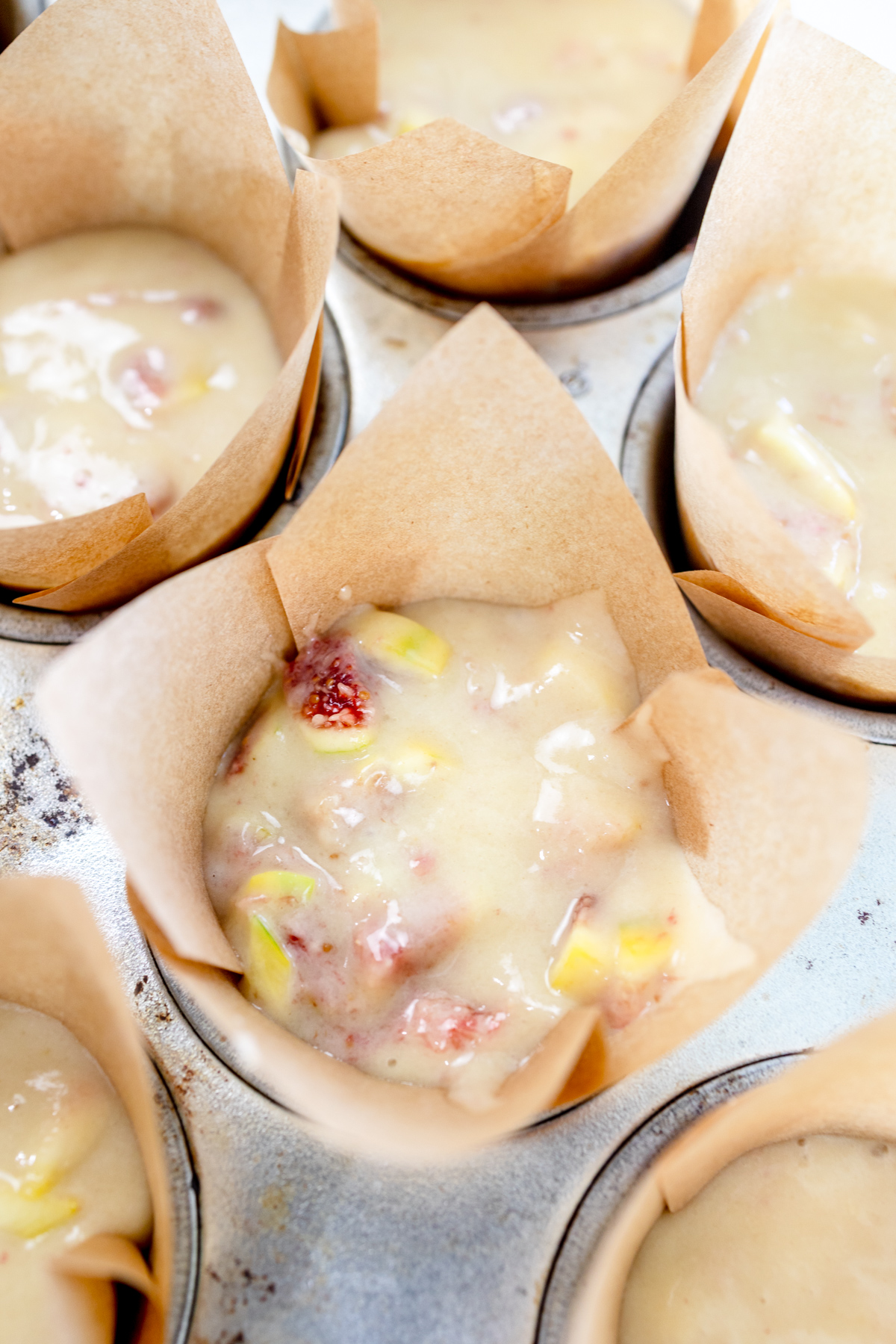 Close up image of fig muffin batter in muffin cases in a muffin tin.
