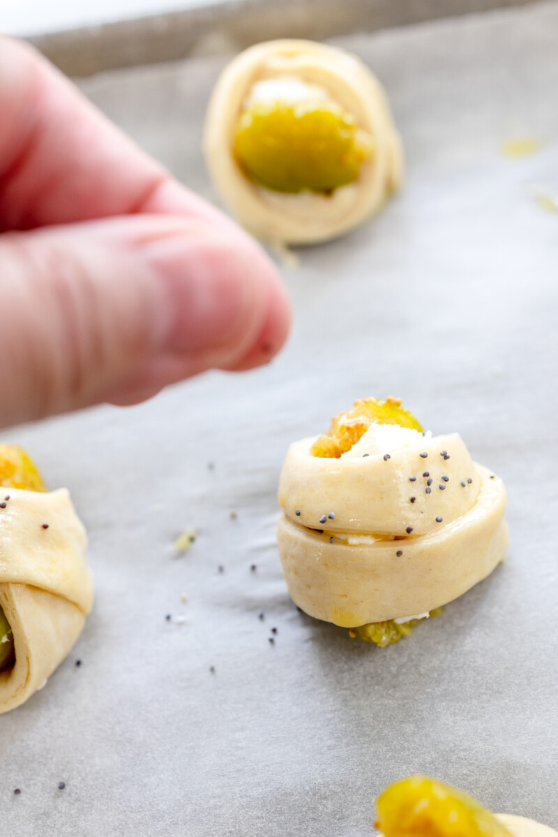 Close up image of unbaked Figs in a Blanket being sprinkled with seasoning.