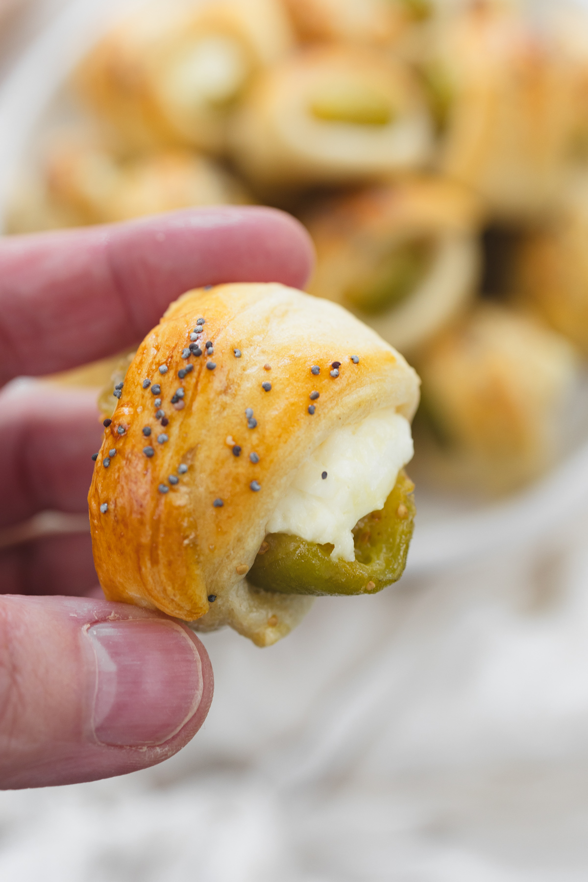 Close up image of a hand holding a Fig in a Blanket.