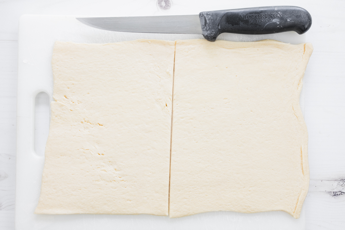 Overhead image of pastry sliced in the middle next to a knife.