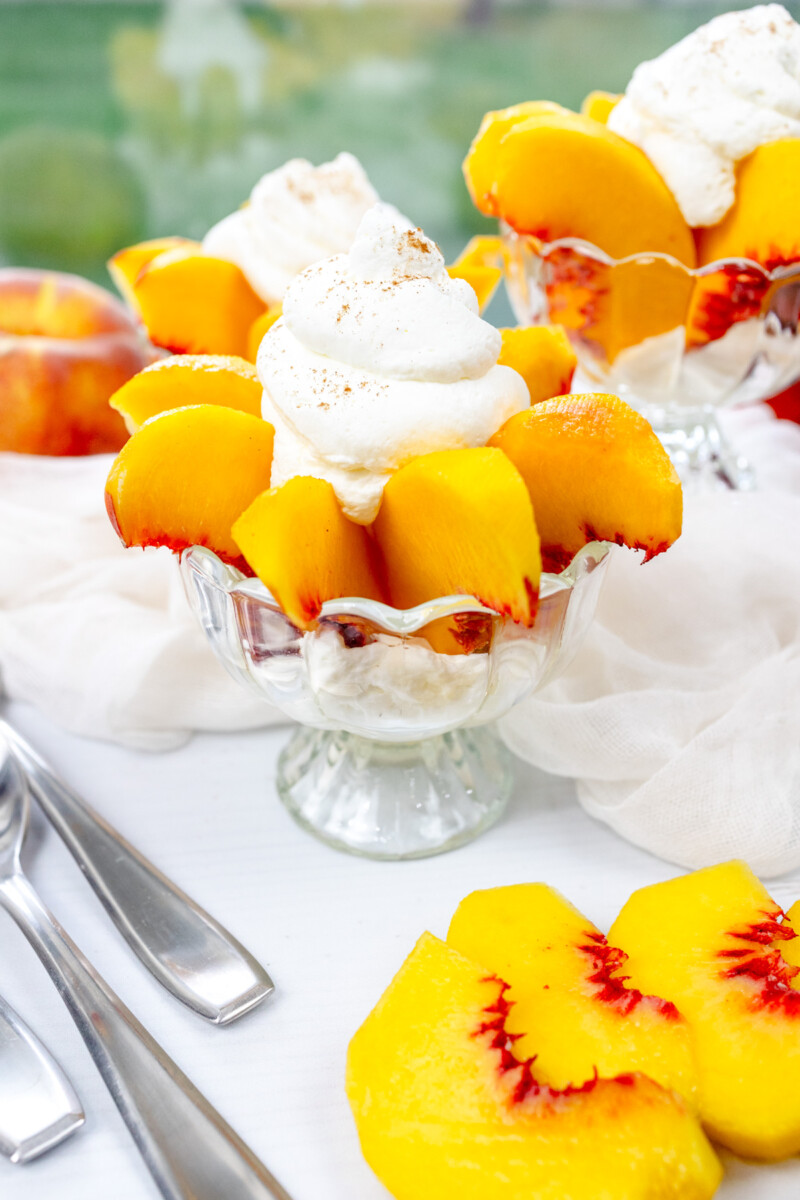 Angled view of Peaches and Cream in a bowl surrounded by peaches and white decorations.