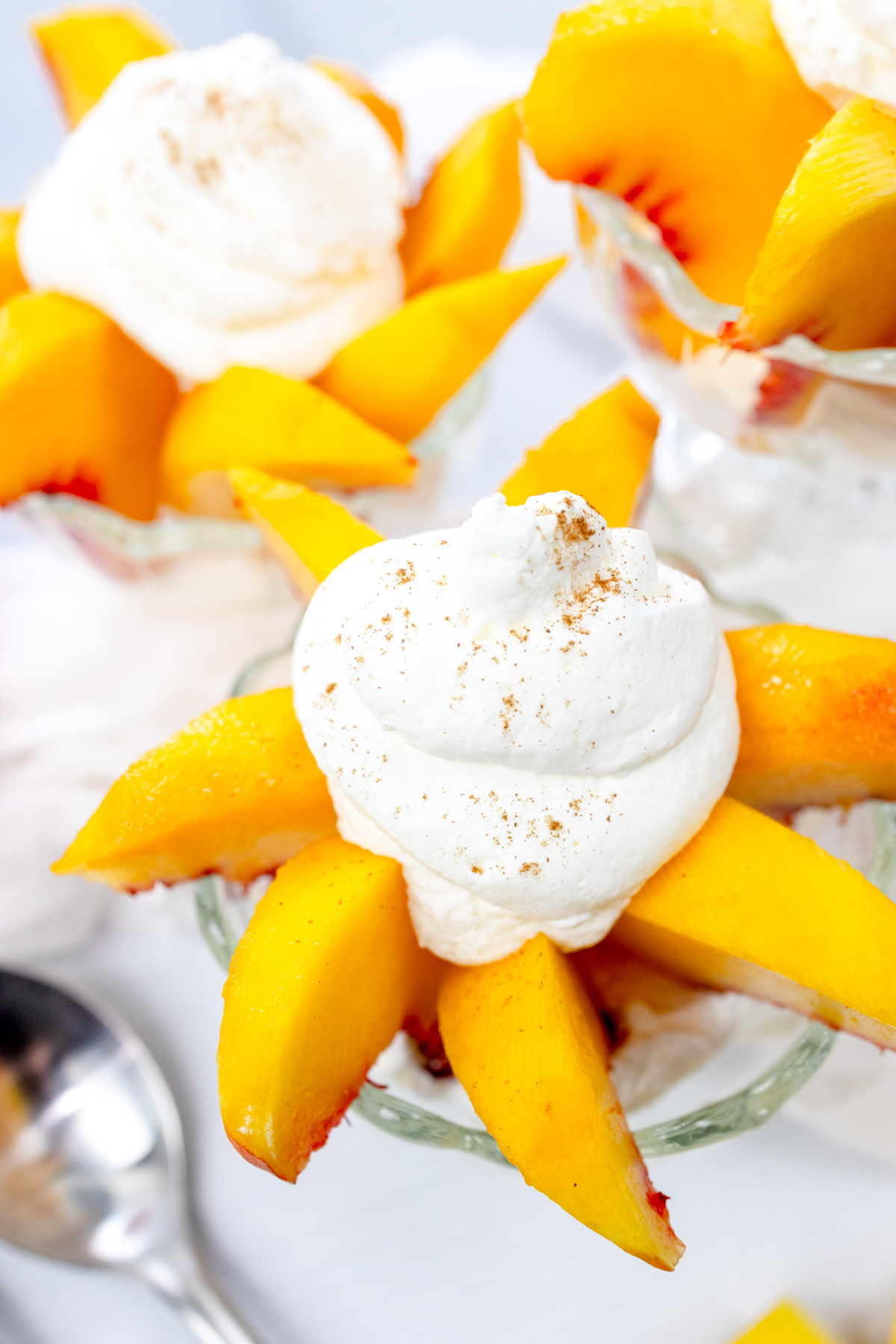 Angled view of bowls of peaches and cream surrounded by peaches and white decorations.