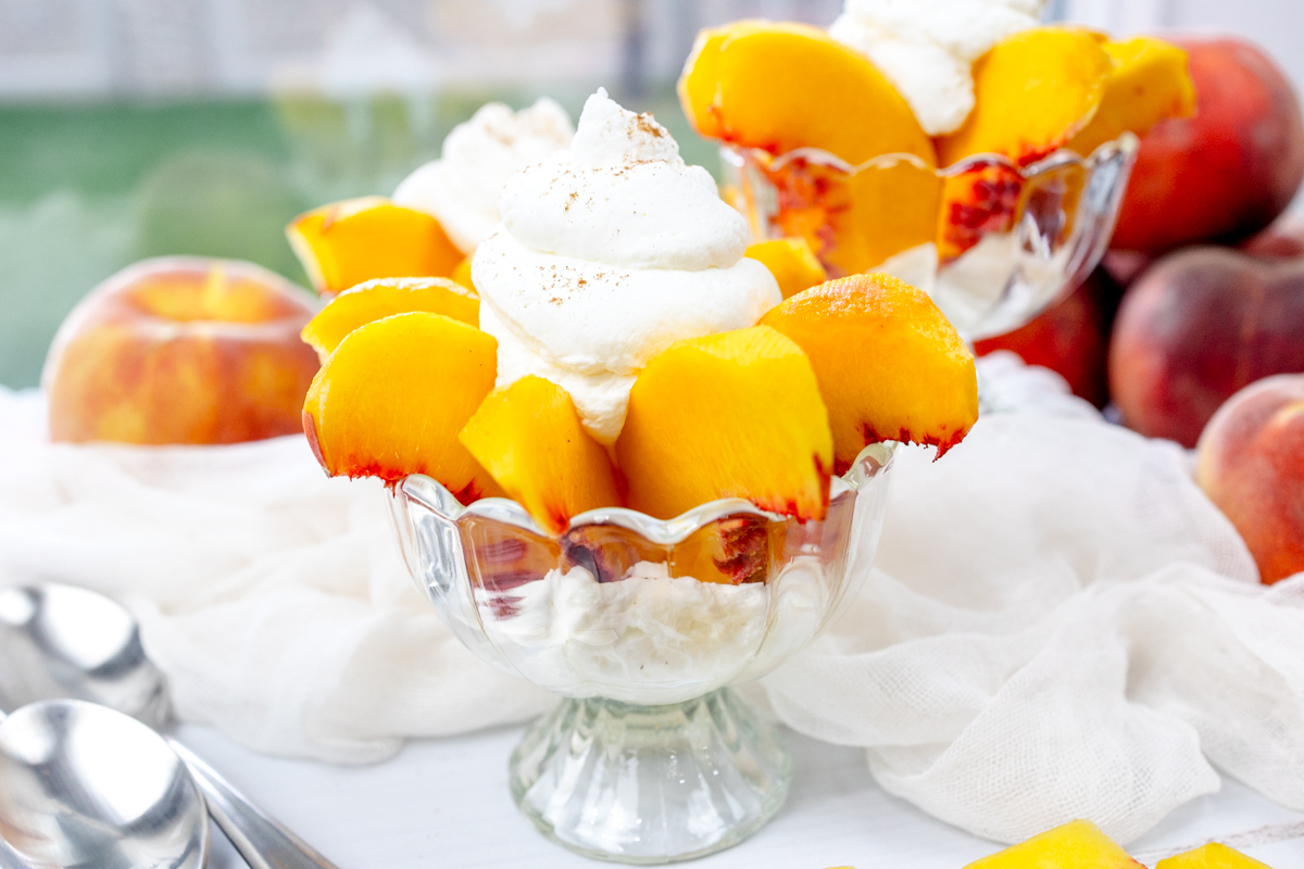 Wide view of Peaches and Cream in a bowl surrounded by peaches and white decorations.