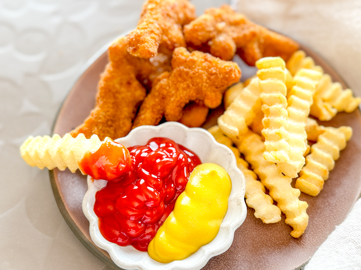 Air Fryer Crinkle Cut Fries on plate with Dino Nuggets and dipping sauces.
