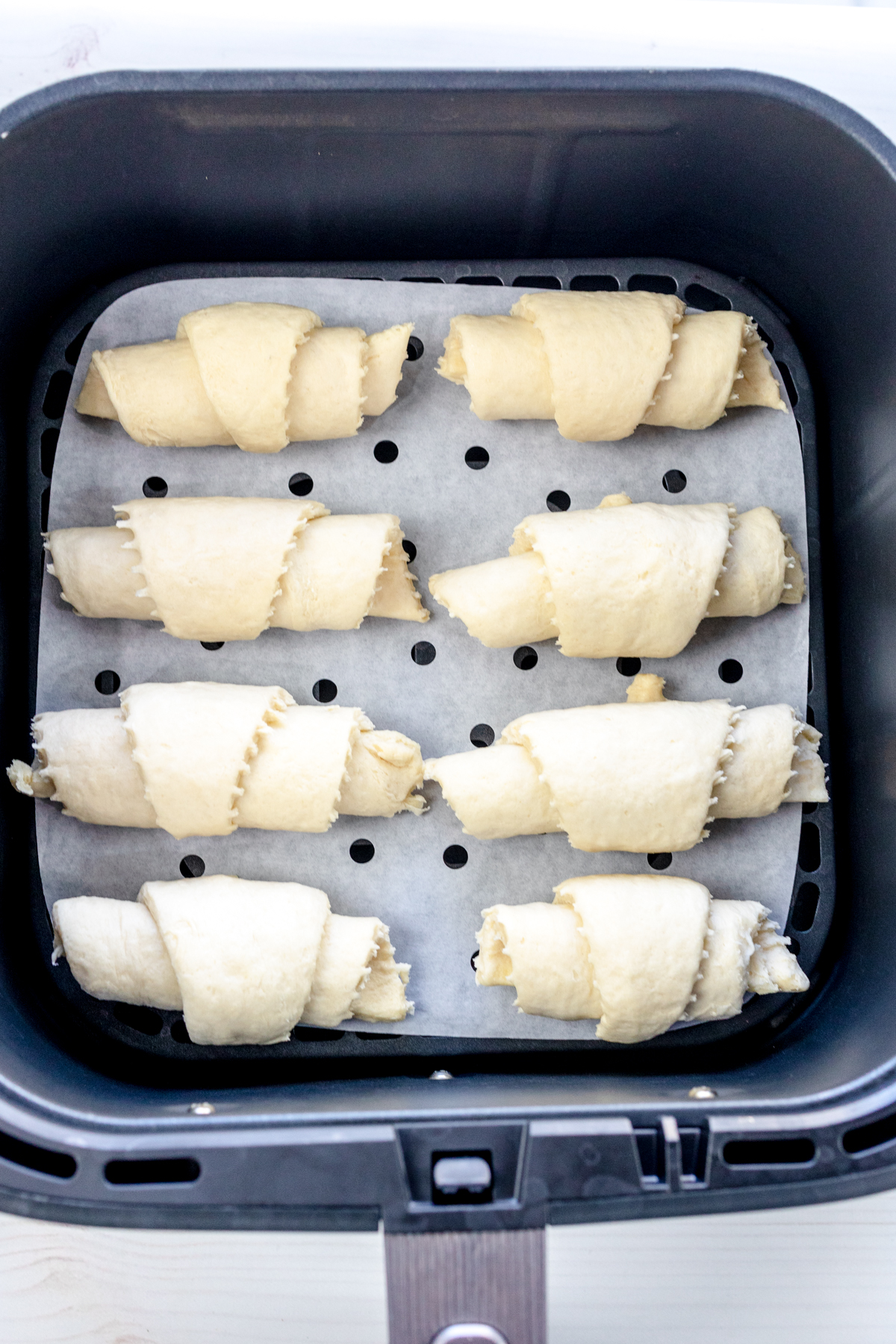 Overhead view of uncooked crescent rolls in an air fryer basket.