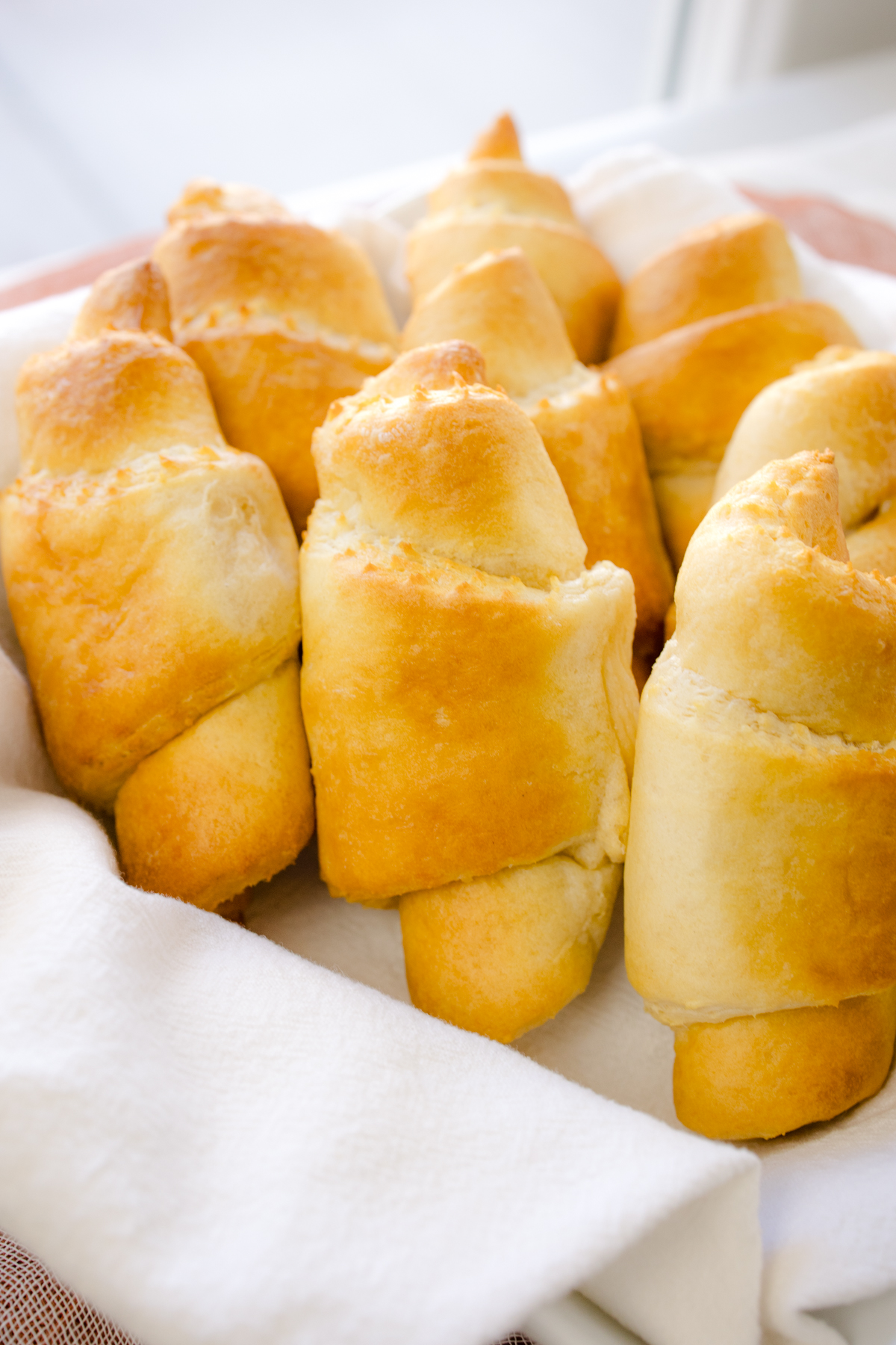 Angled view of cooked crescent rolls wrapped in a white fabric.