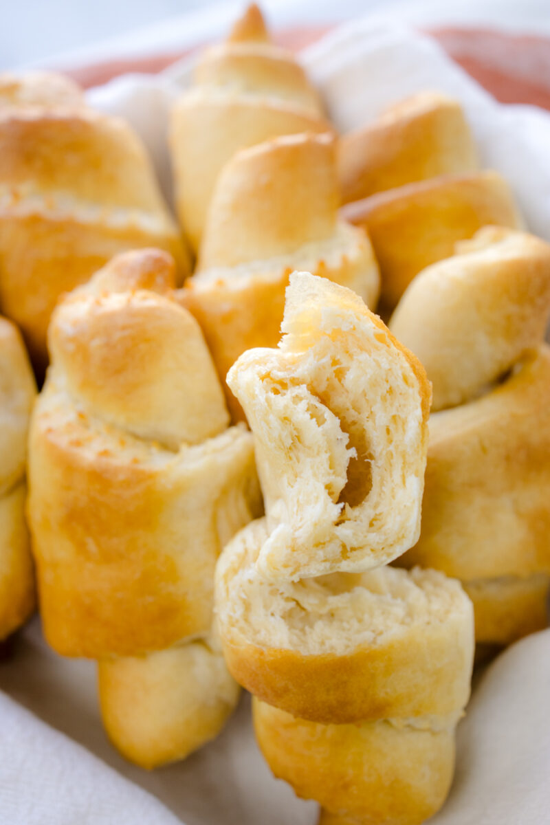 Close up view of crescent rolls in white fabrice, where the foremost roll is sliced in half to reveal the middle.