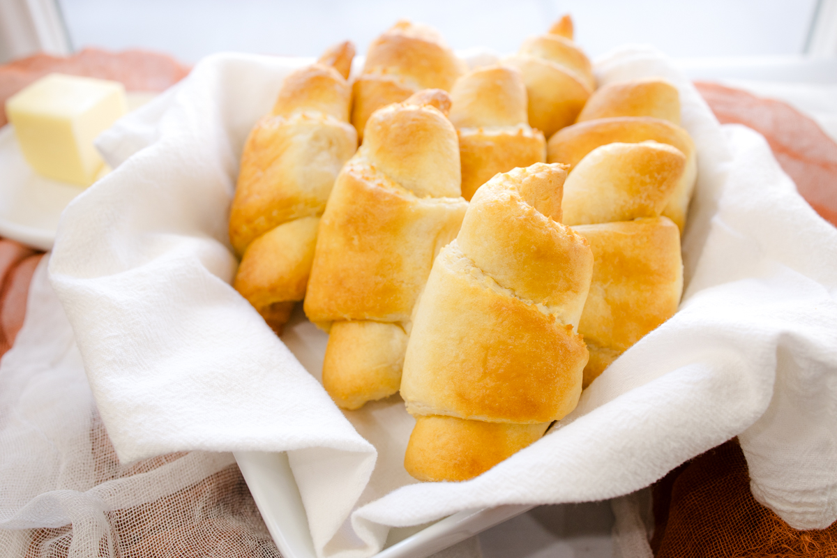 Angled view of cooked crescent rolls wrapped in a white fabric.