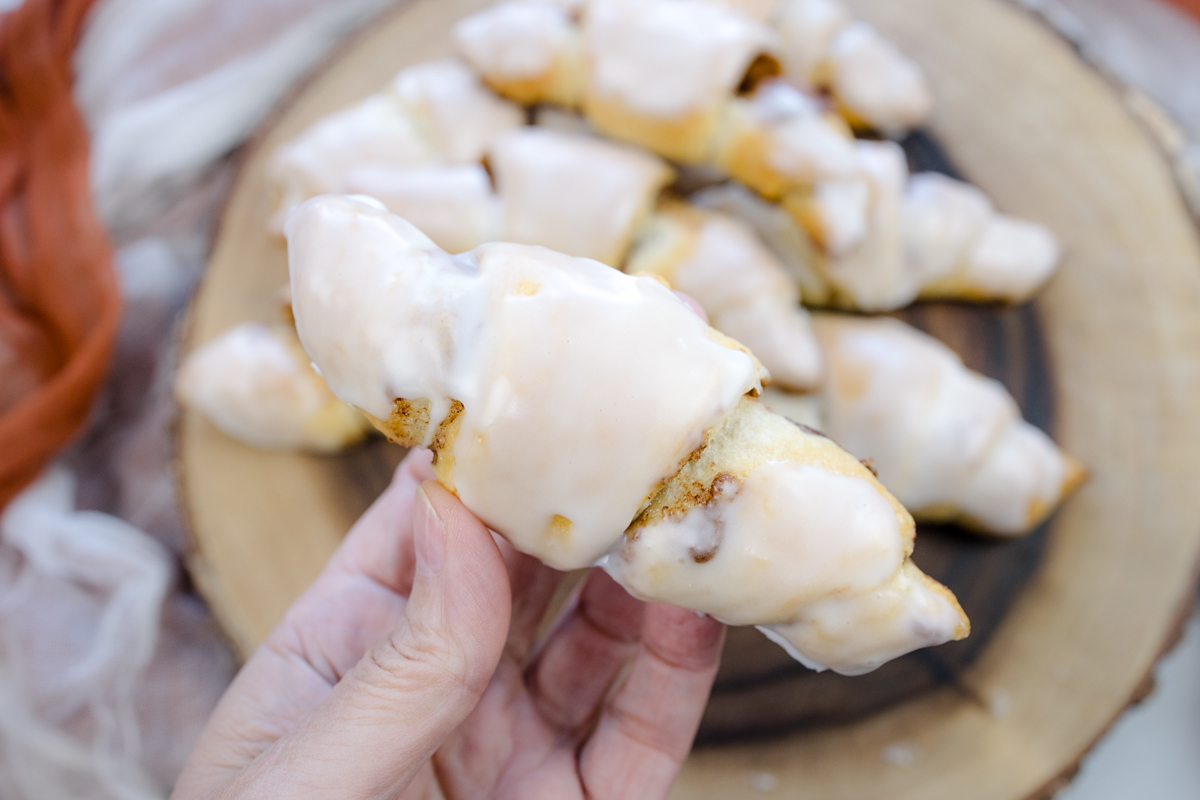 Close up view of a hand holding a Cinnamon Crescent roll.