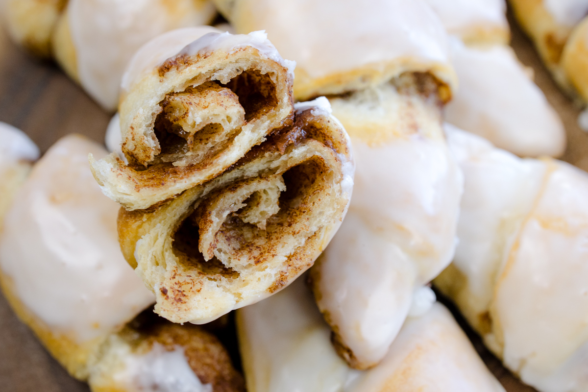 Close up view of a pile of Cinnamon Crescent Rolls with the top one sliced in half to reveal the middle.