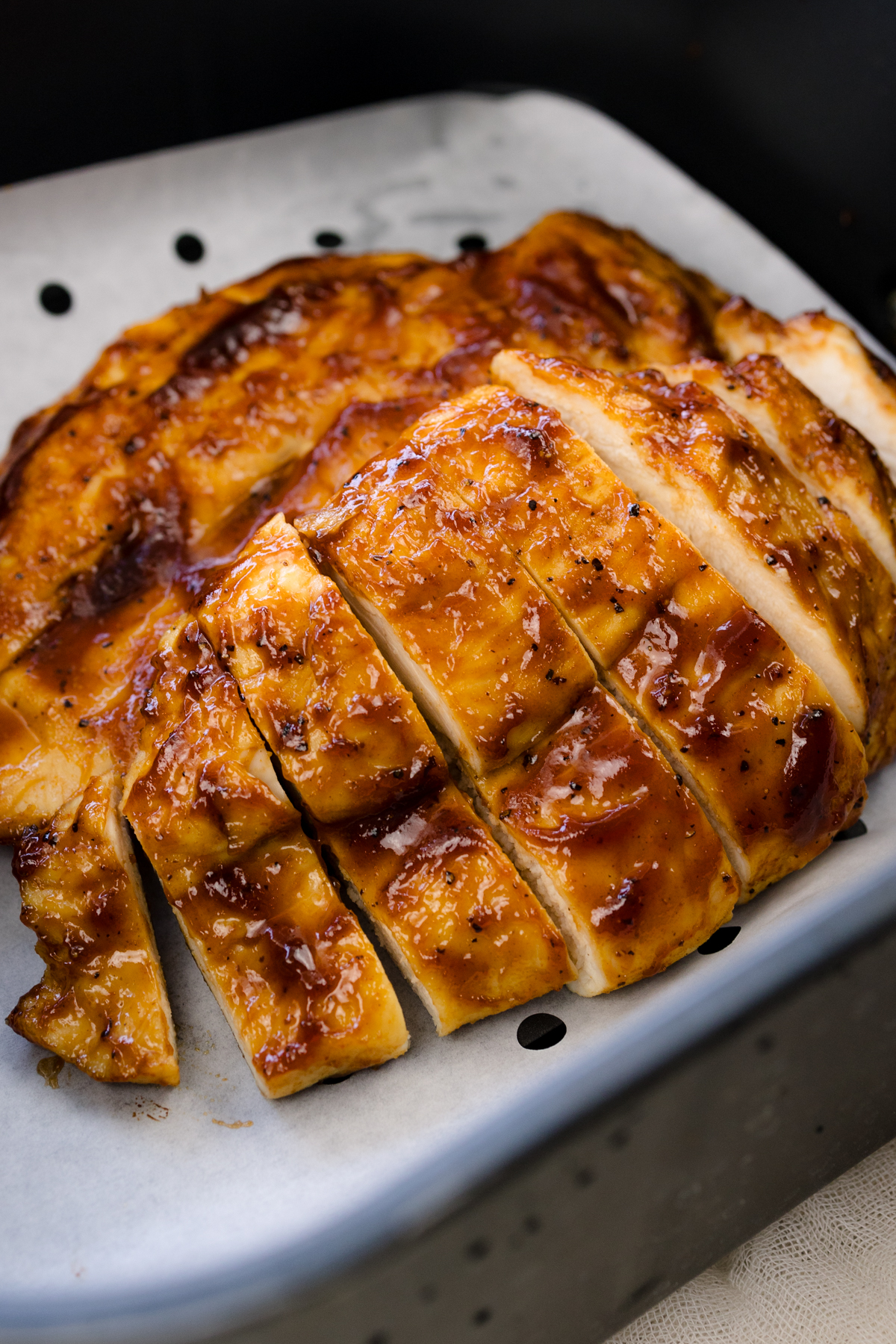 Close view of cooked BBQ Chicken in an air fryer basket.