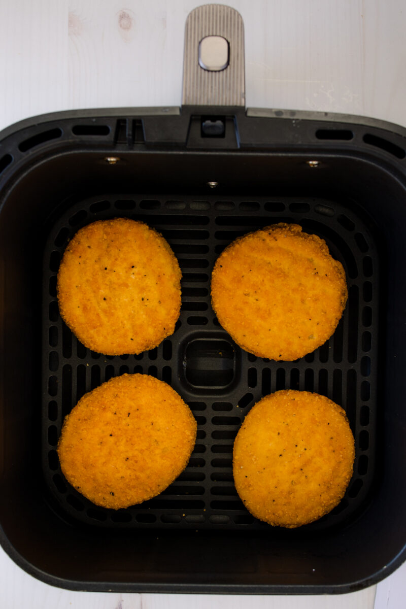 Overhead image of four chicken patties in an air fryer basket.