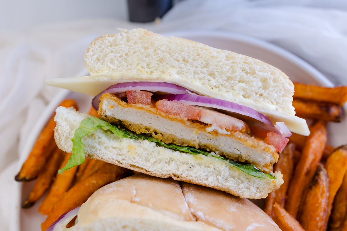 Overhead image of a chicken patty sandwich on a plate with sweet potato fries.