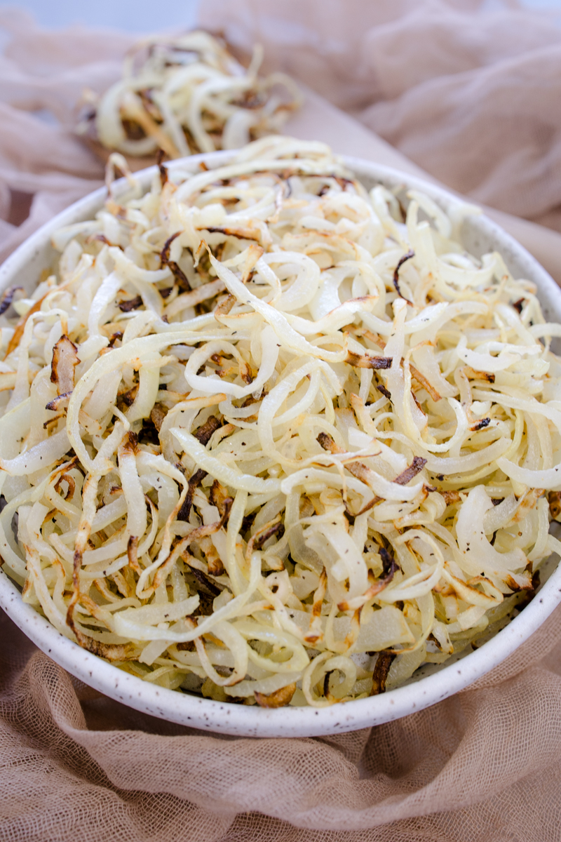 Angled view of a white plate full of Air Fryer Onions.