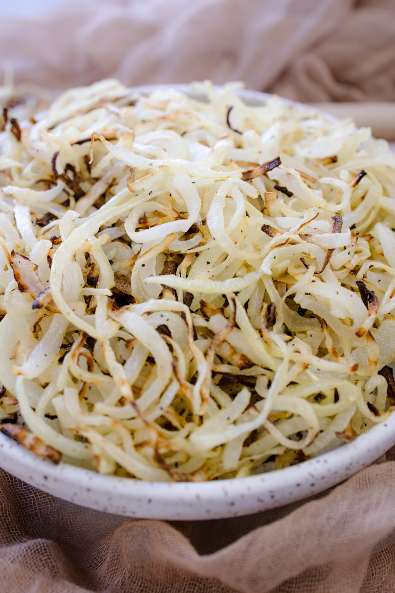 Angled view of a white plate full of Air Fryer Onions.