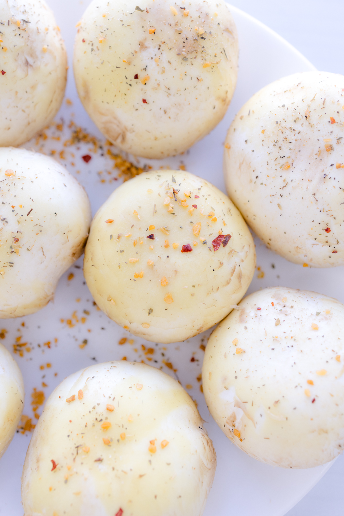 Overhead image of mushroom caps sprinkled with Garlic Herb Blend Seasonings.