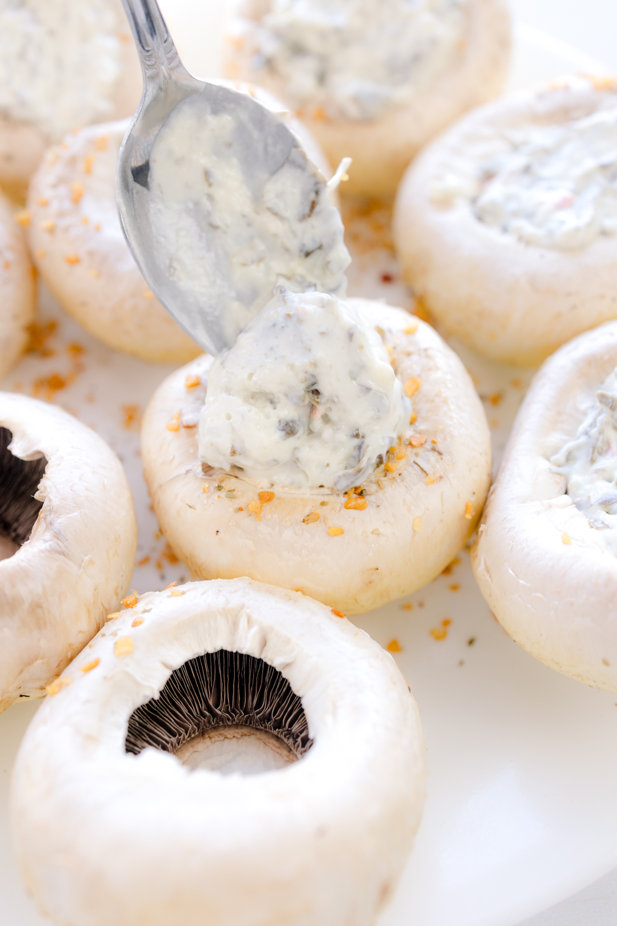 Close up image of mushrooms being filled with spinach artichoke dip.