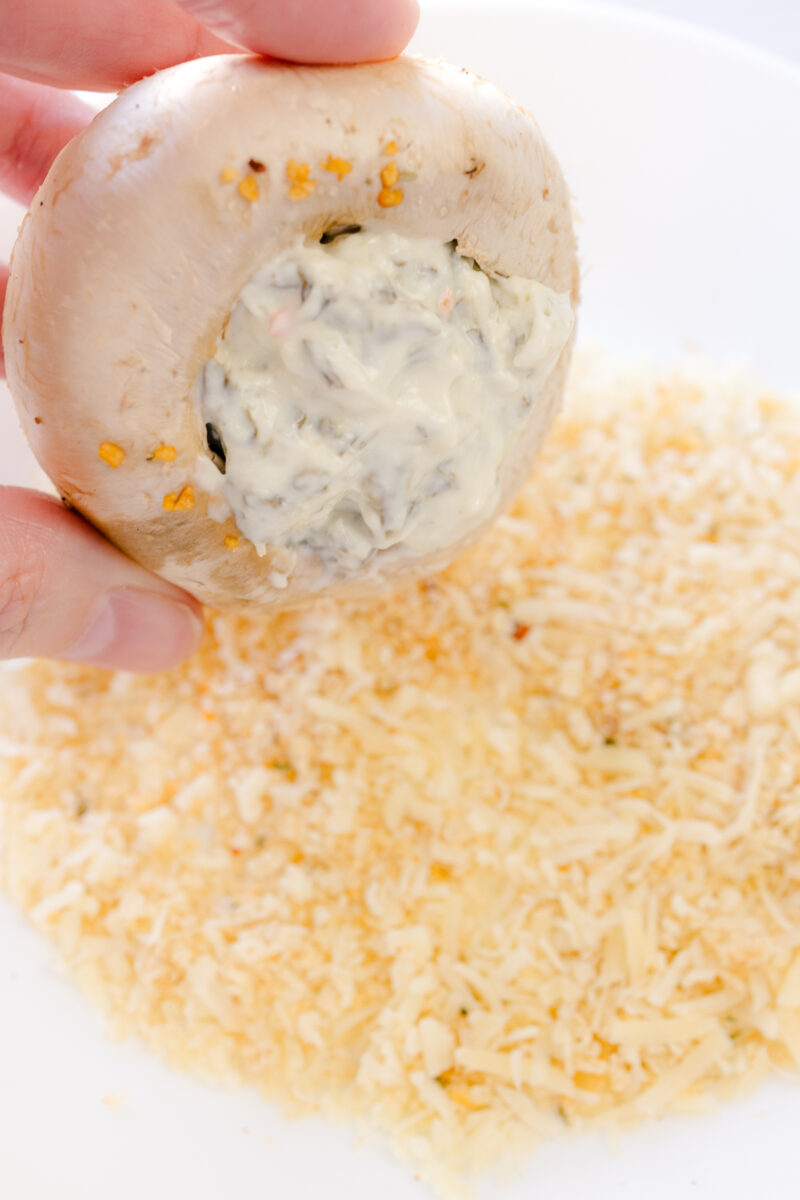 Close up image of a mushroom being coated with Parmesan & Panko breadcrumbs.