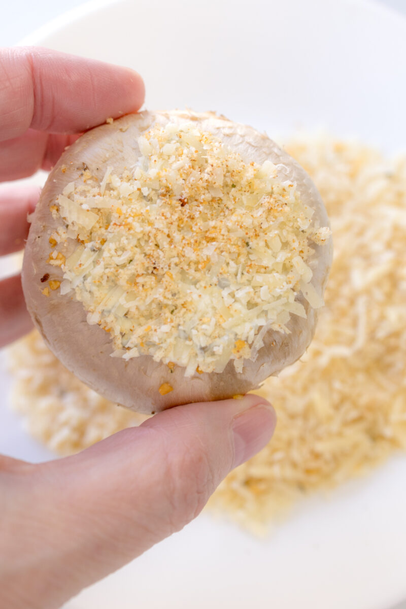 Close up image of a mushroom being coated with Parmesan & Panko breadcrumbs.
