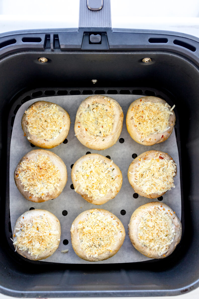 Overhead image of Air Fryer Stuffed Mushrooms in an air fryer basket lined with parchment paper.