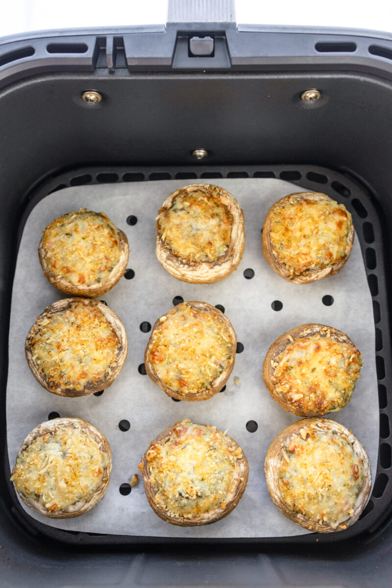 Overhead image of Air Fryer Stuffed Mushrooms in an air fryer basket lined with parchment paper.