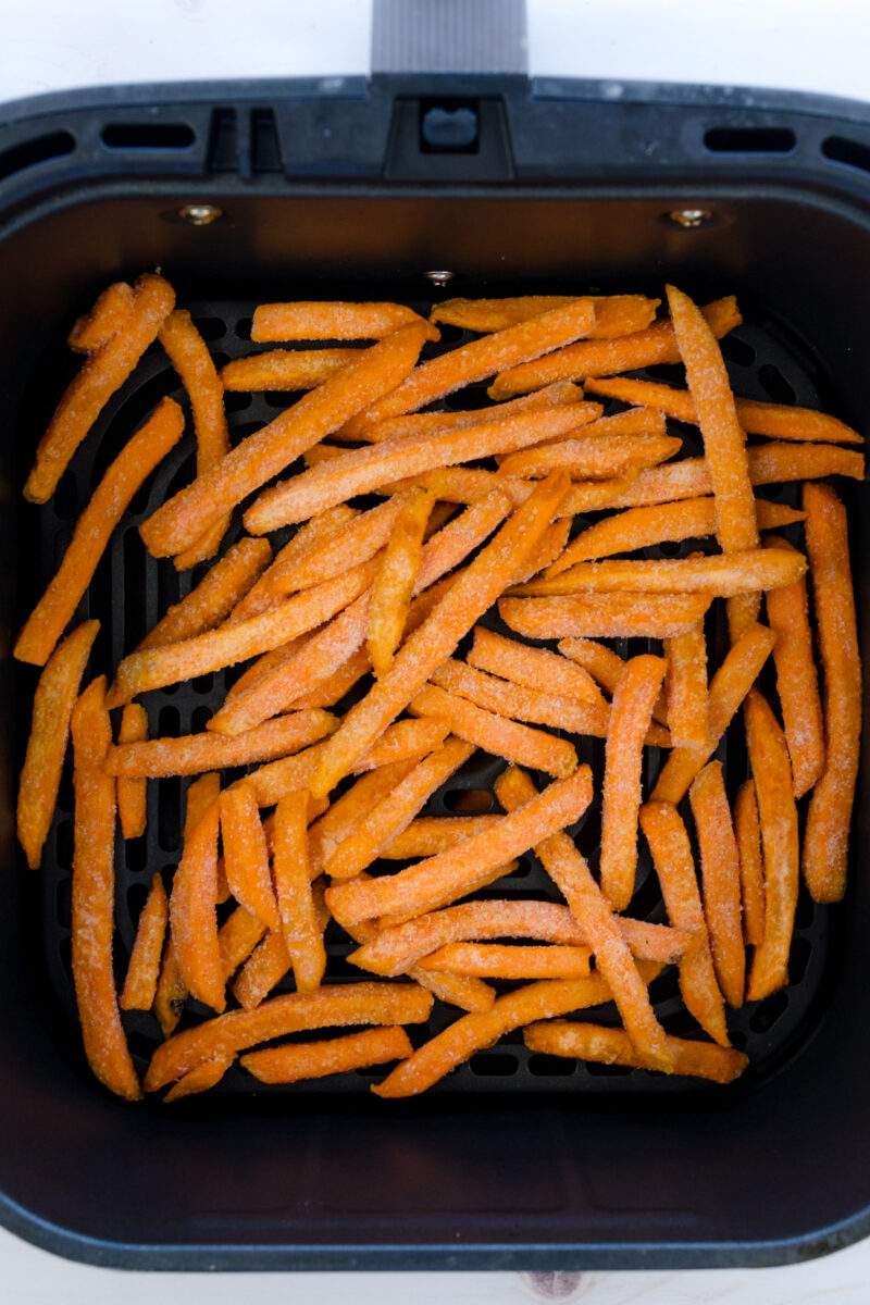 Angled view of sweet potato fries in an air fryer basket.