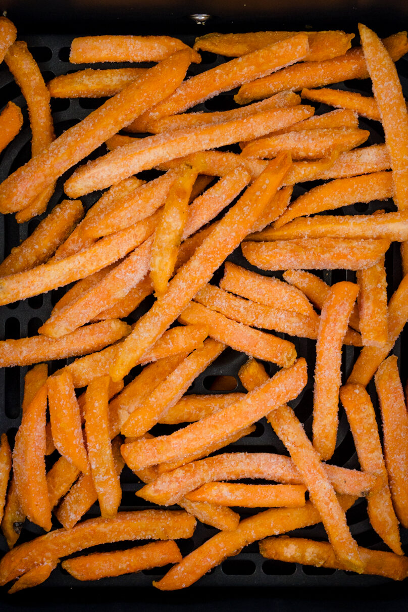 Angled view of sweet potato fries in an air fryer basket.