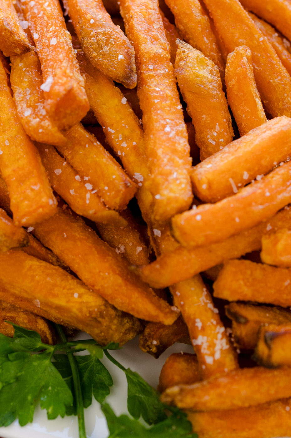 Close-up view of air fried sweet potato fries on a white serving platter.