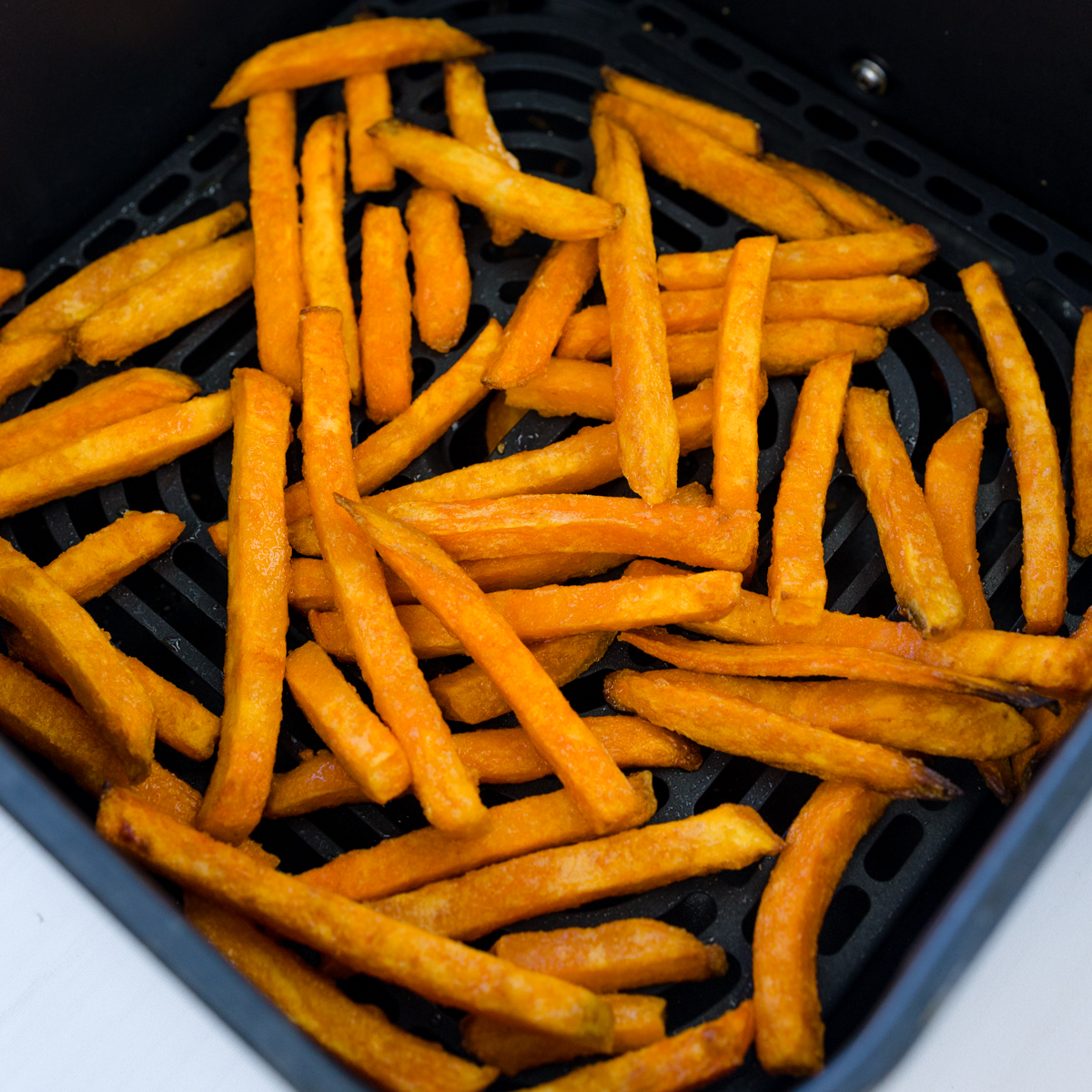 Angled view of sweet potato fries in an air fryer basket.