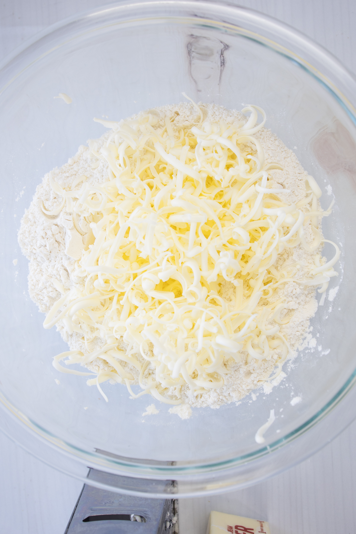 Overhead view of a glass bowl of shredded butter.