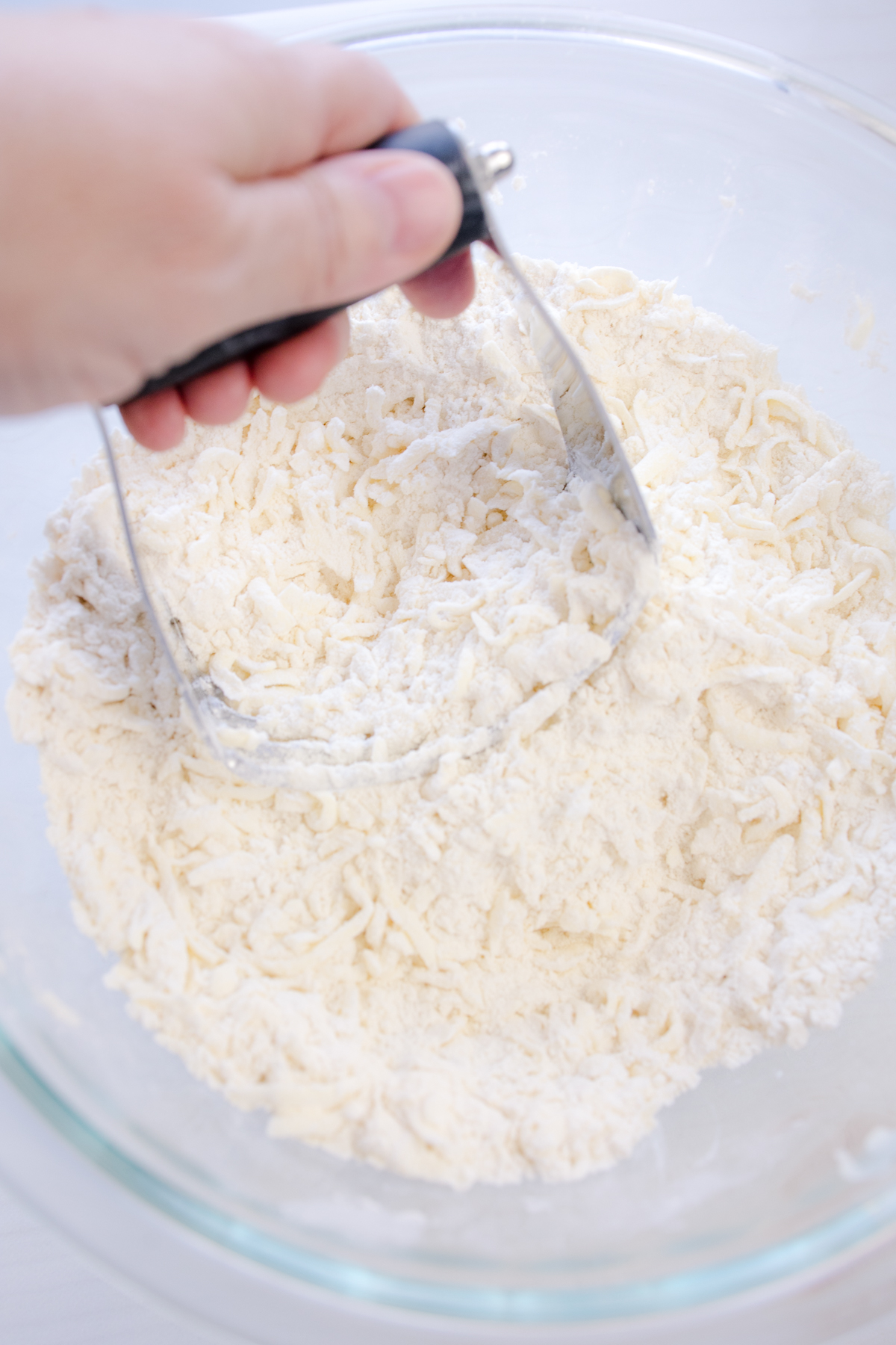 Angled view of dry ingredients being mixed with the shredded butter.