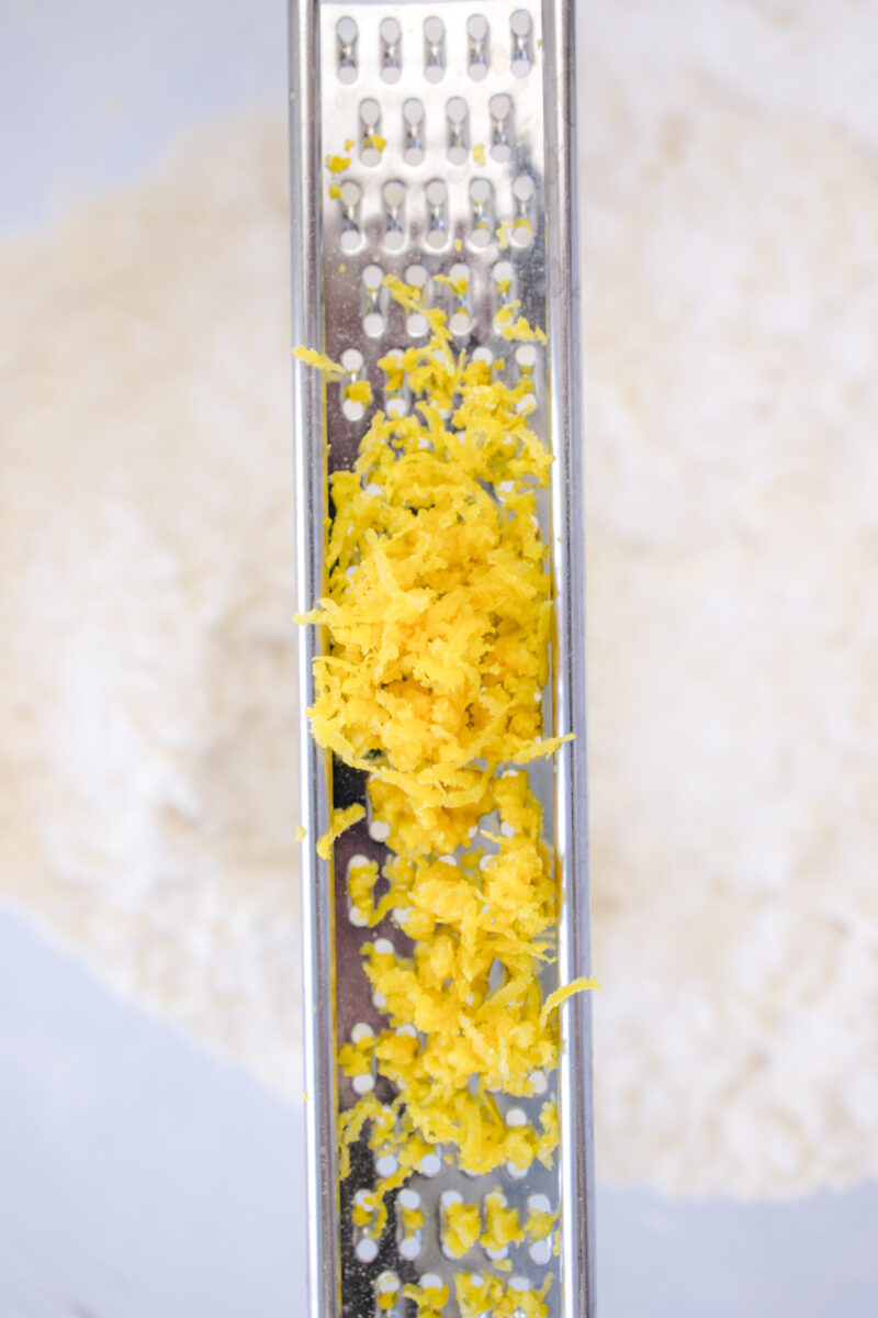 Close view of lemon zest being added to the biscuit dough.