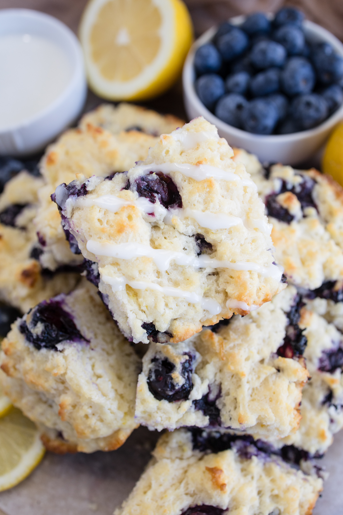 Angled view of Blueberry Biscuits stacked on top of each other, next to blueberries and half a lemon.