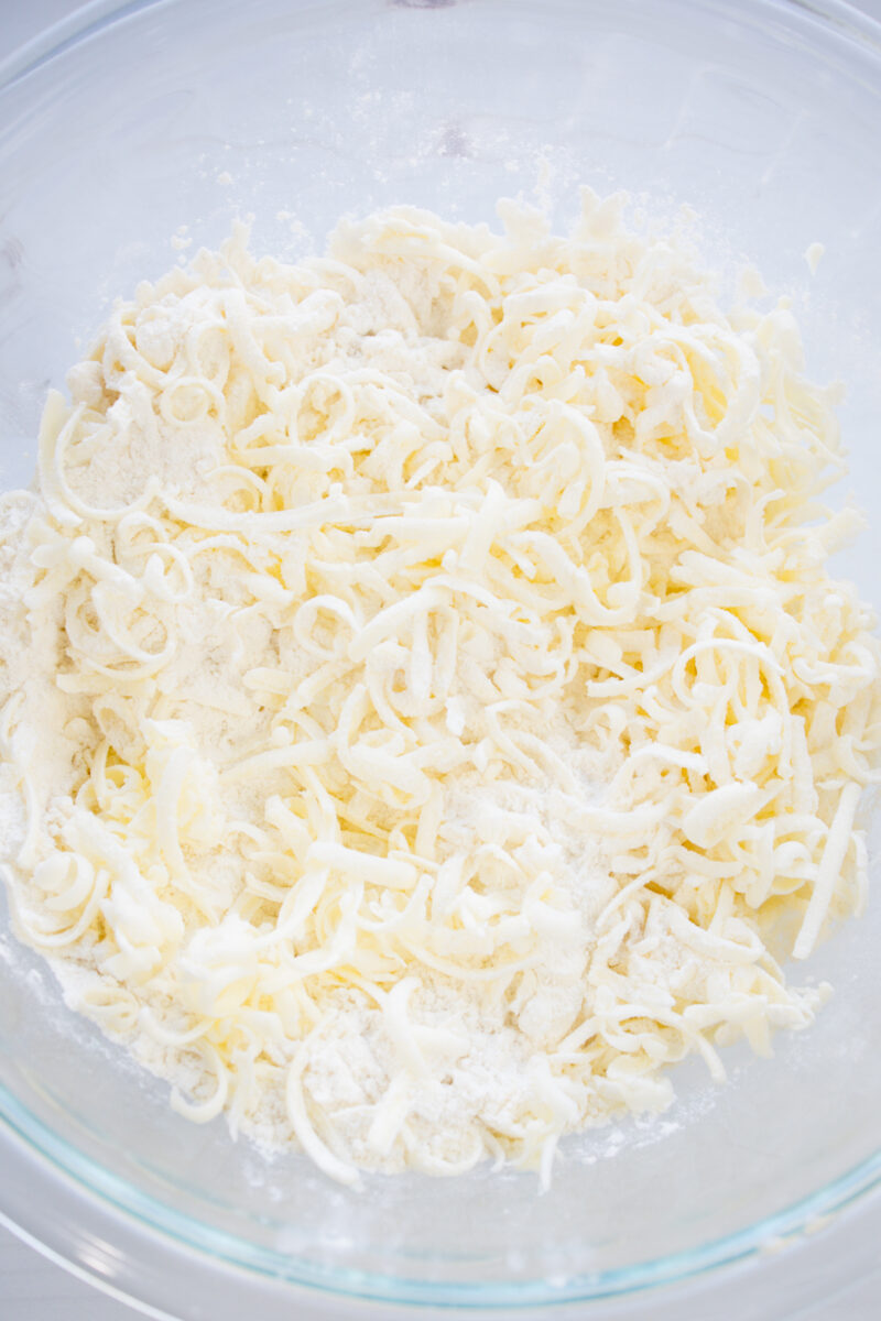 Overhead view of a glass bowl of shredded butter and flour.