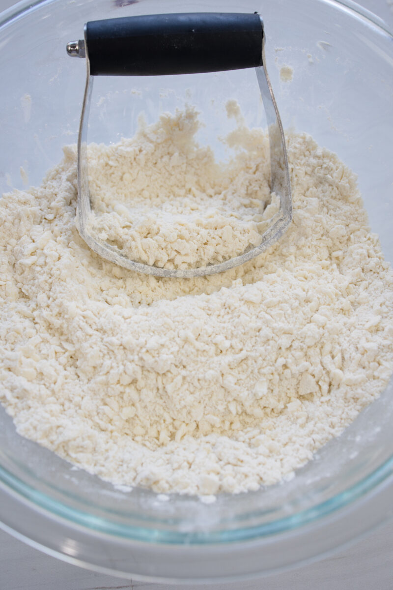 Angled view of dry ingredients being mixed with the shredded butter.